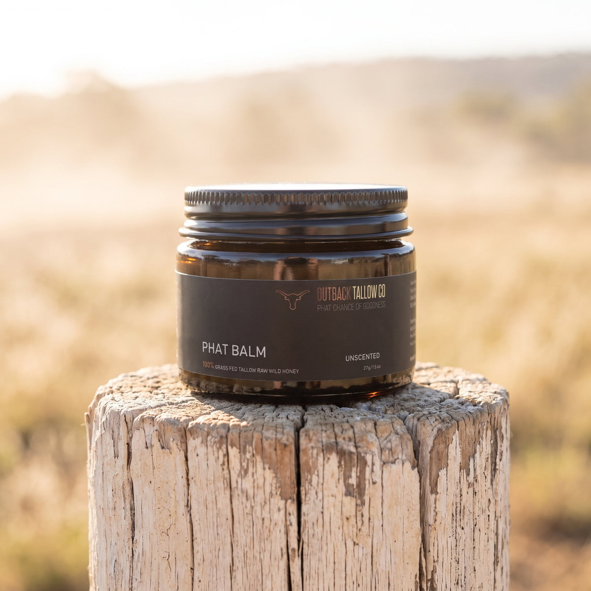 PHAT Balm jar on a weathered fence post in a dry paddock (AI-generated image)
