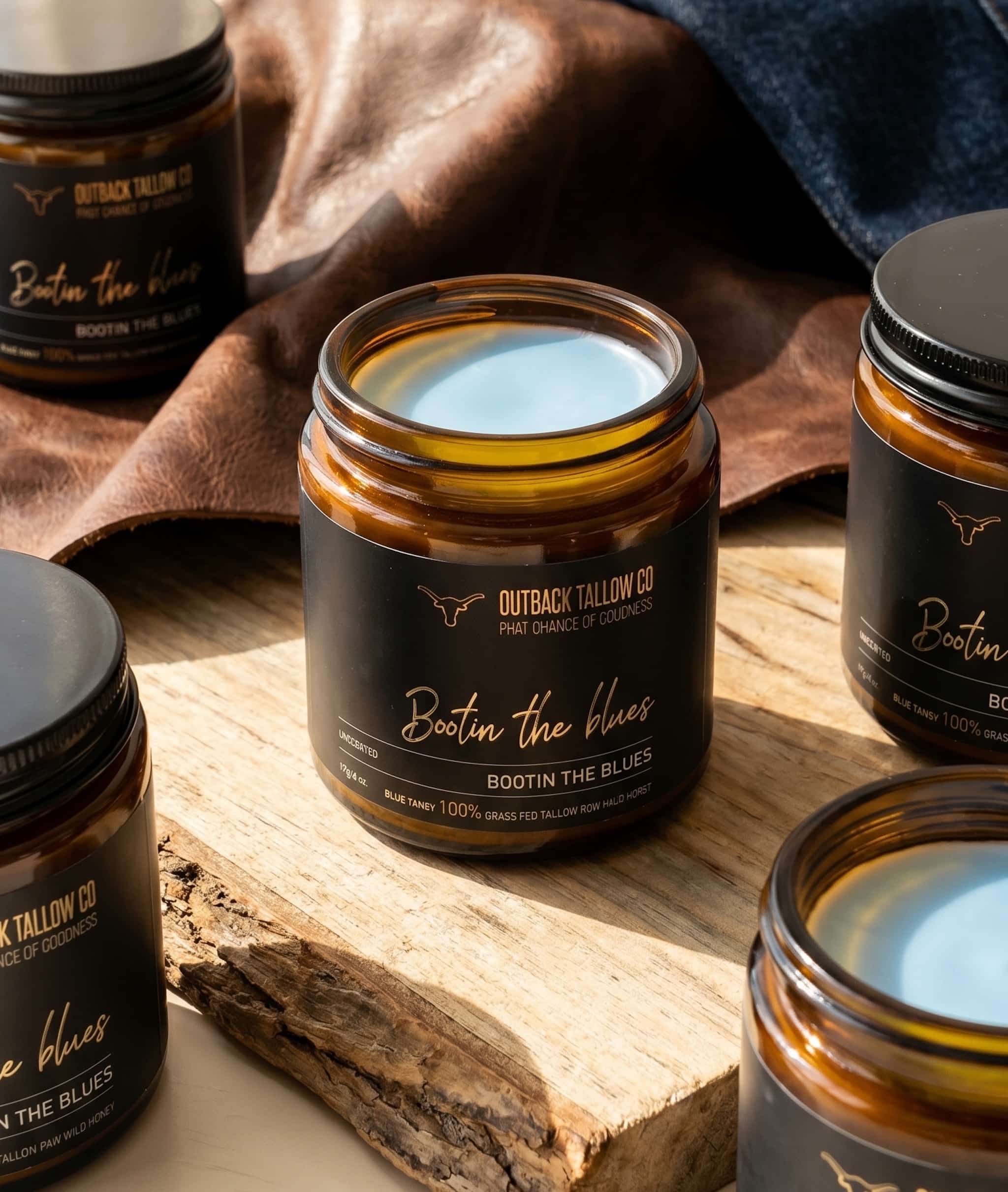 Bootin the Blues grass-fed beef tallow balm for sensitive skin eczema psoriasis and rosacea multiple jars arranged on timber board with leather background natural skincare no synthetic fragrance fast shipping Australia wide – Outback Tallow Co Townsville Queensland Australia