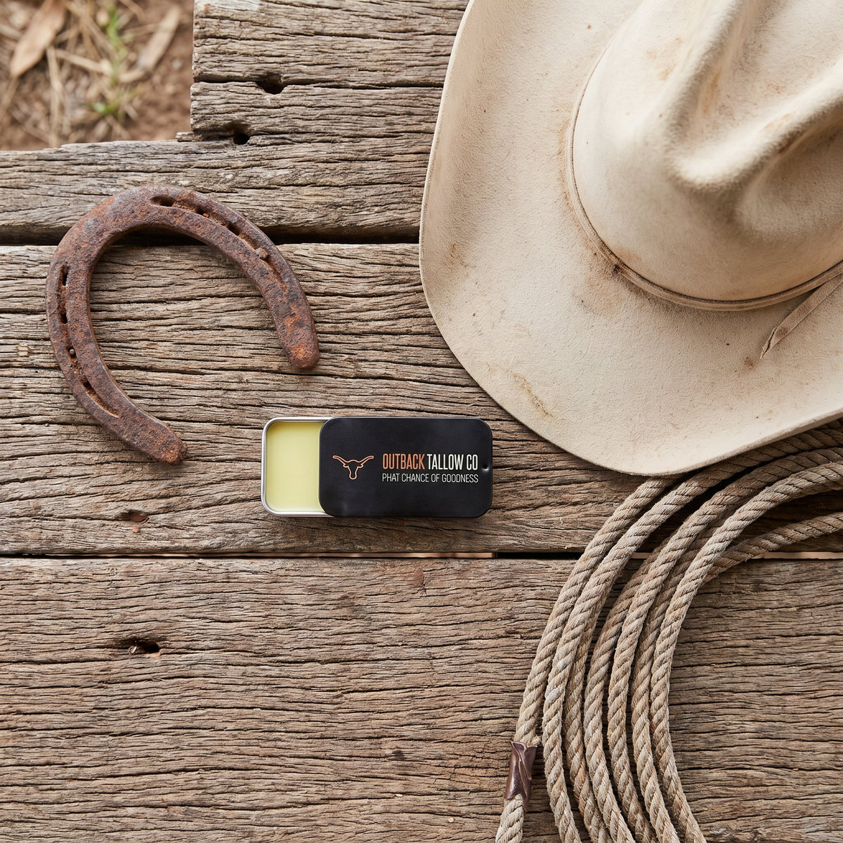 The OG slide tin on timber boards beside a cowboy hat, horseshoe and rope (AI-generated image)