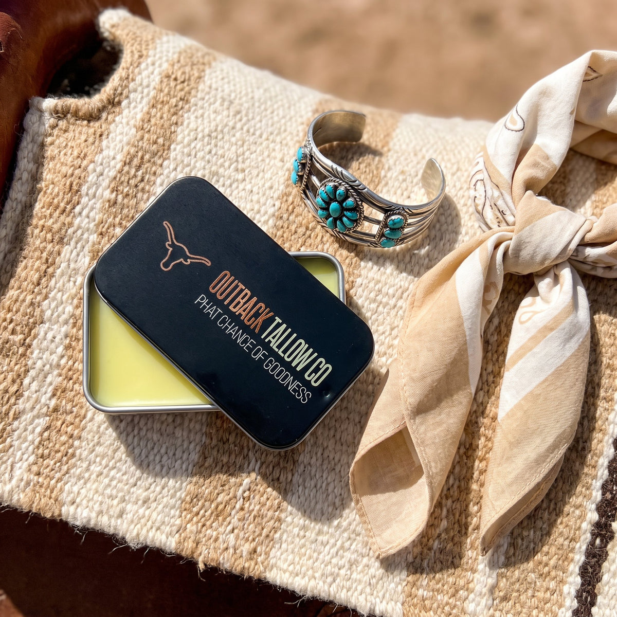 The OG slide tin on a woven saddle blanket with a turquoise cuff and scarf (AI-generated image)