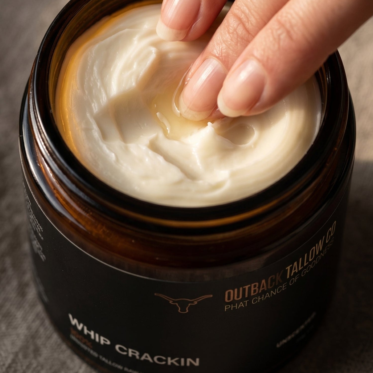 Hand scooping whipped tallow from a jar labeled &
